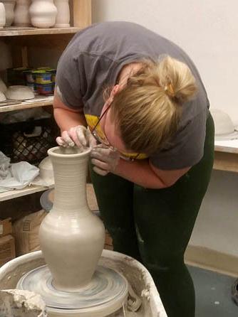 A student works on a thrown piece of artwork